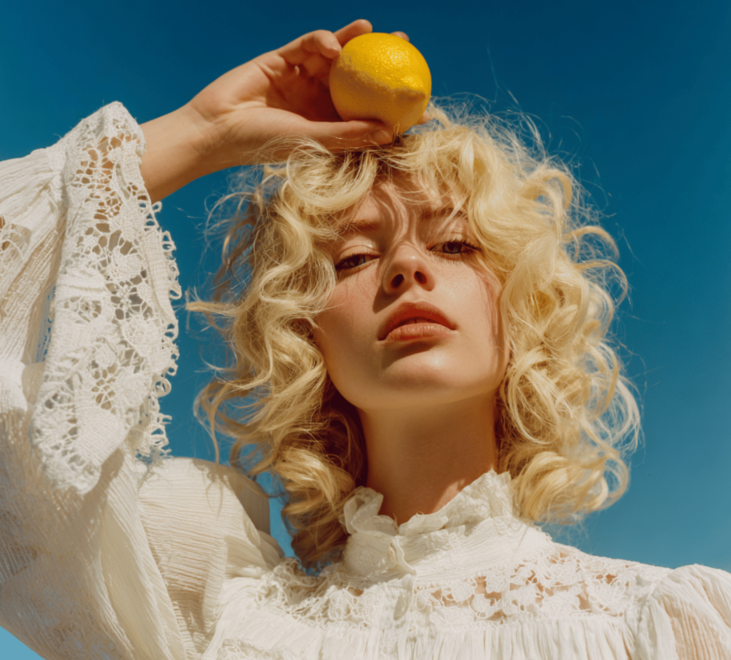 Woman holding a lemon above her head against a clear blue sky